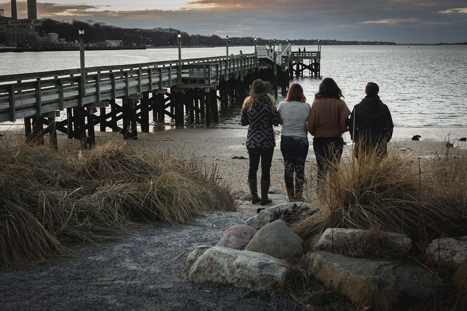 Four women standing next to the pier in Port Jefferson New York and looking into the ocean