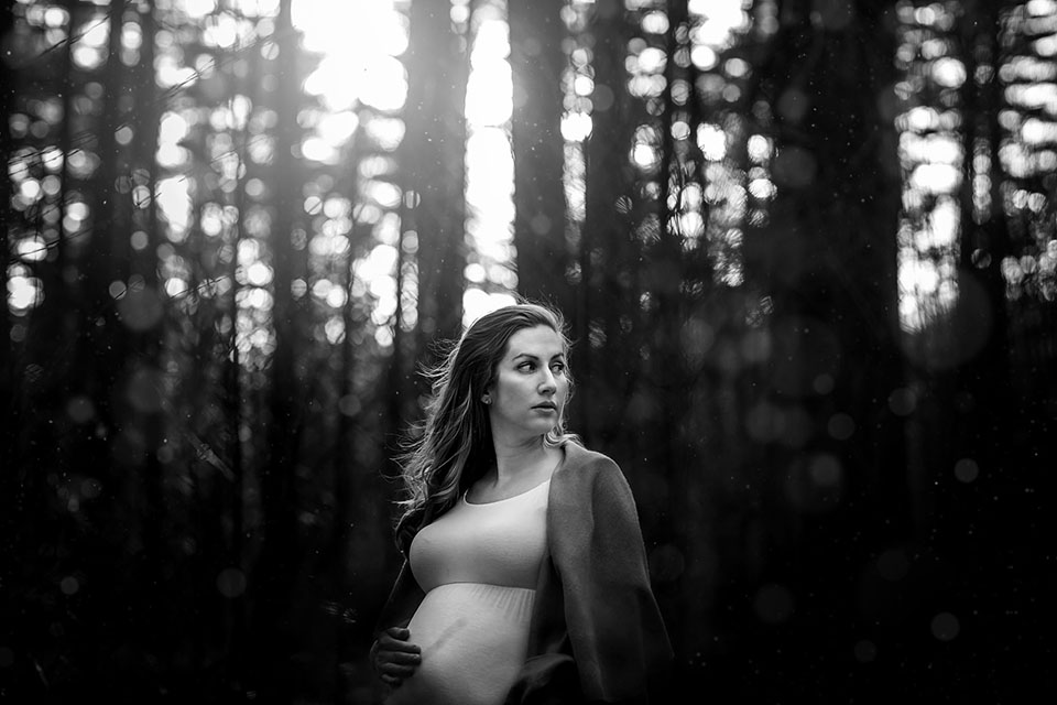 Pregnant woman taking photos in the woods in a beautiful maternity gown