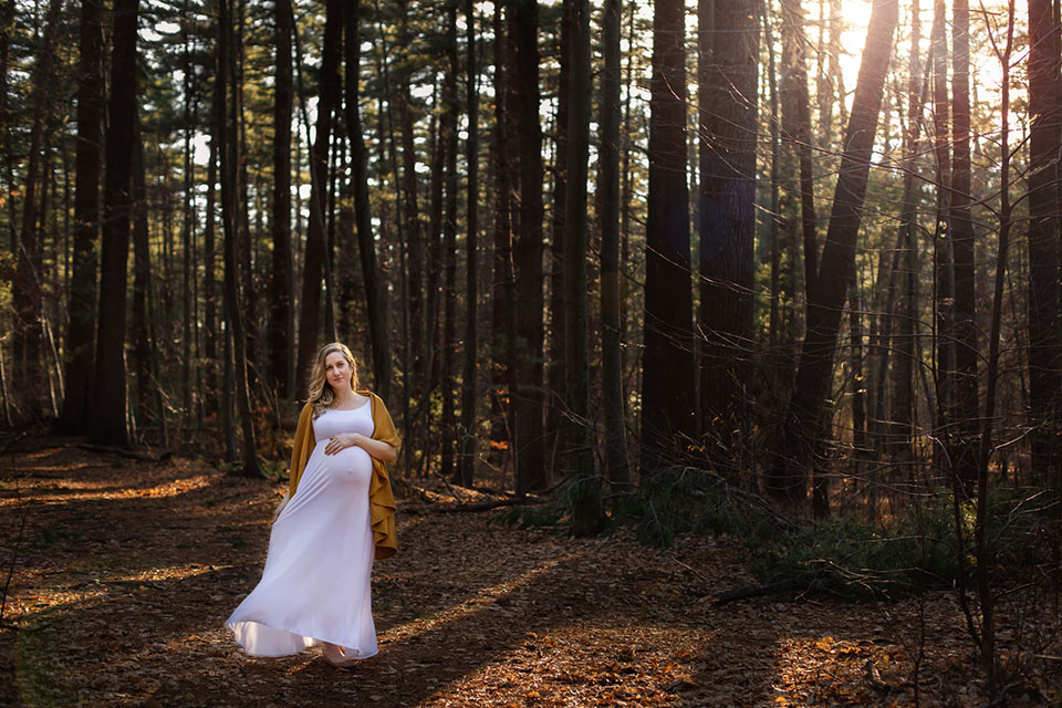 Pregnant woman taking photos in the woods in a beautiful maternity gown